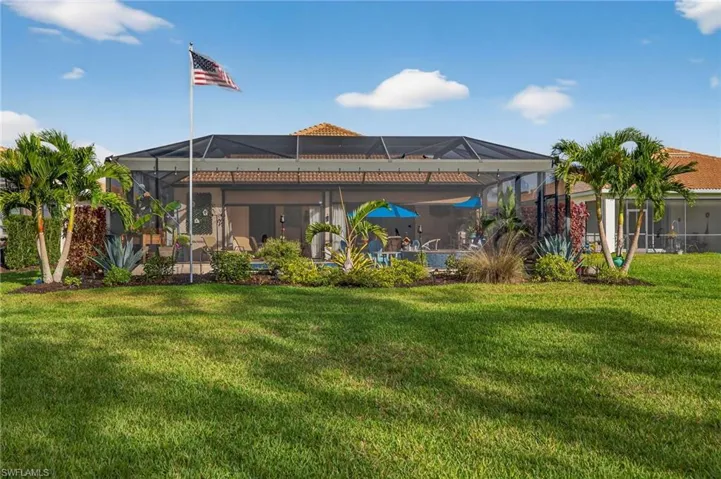 Rear view of property featuring a sunroom, a yard, and glass enclosure