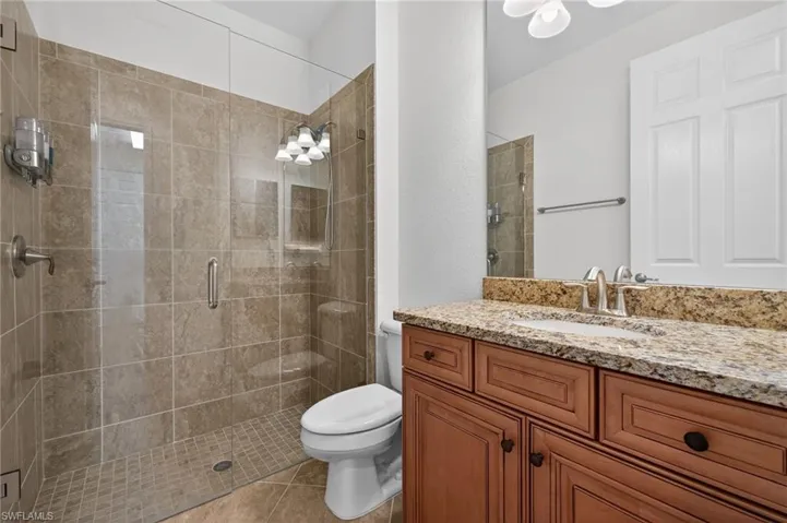 Bathroom with vanity, a stall shower, a textured wall, and tile patterned flooring