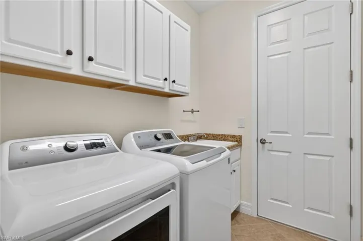 Laundry room with washing machine and dryer, light tile patterned floors, and cabinet space