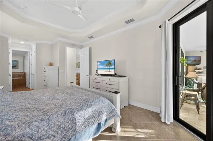 Bedroom featuring ornamental molding, access to exterior, a tray ceiling, and ceiling fan