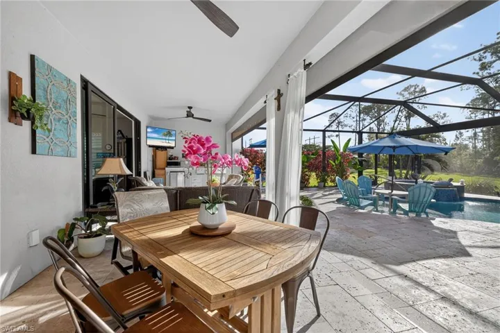 View of patio / terrace featuring a sunroom, an outdoor pool, outdoor dining space, a ceiling fan, and a lanai