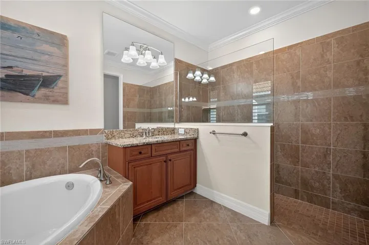 Bathroom with vanity, crown molding, walk in shower, a garden tub, and light tile patterned floors