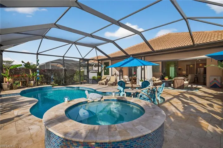 Combined pool / hot tub with a sunroom, glass enclosure, and a patio