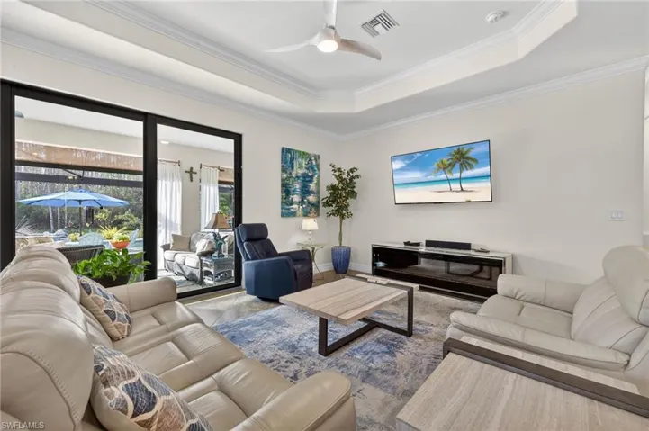 Living area featuring a ceiling fan, crown molding, and a tray ceiling