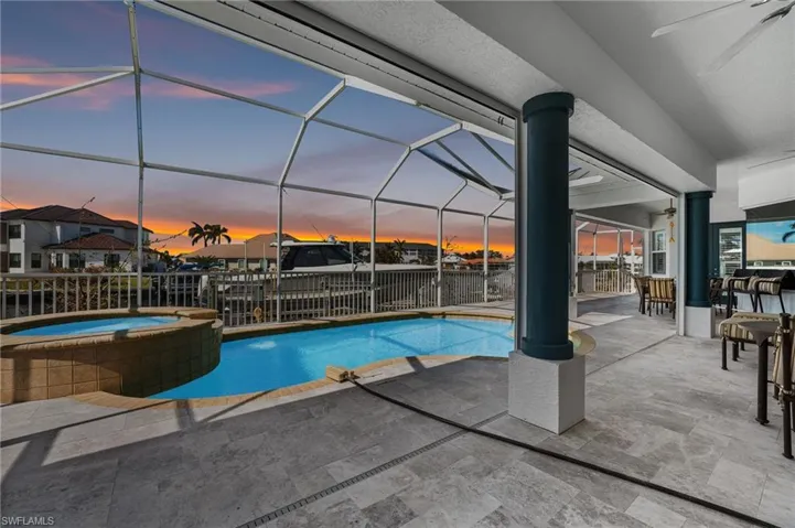Pool at dusk featuring a new pavered pool deck, a heated pool and spa, large covered space for relaxing and entertaining.