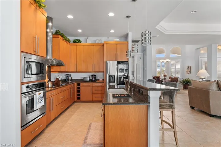 Kitchen with wall chimney exhaust hood, sink, a kitchen bar, decorative light fixtures, and appliances with stainless steel finishes
