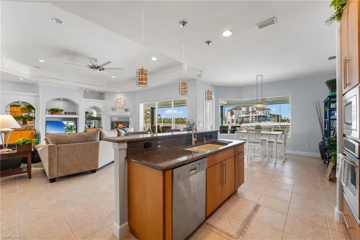 Kitchen with hanging light fixtures, stainless steel appliances, a tray ceiling, sink, and ceiling fan