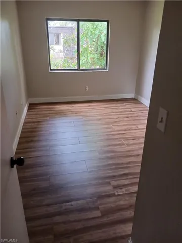 Empty room featuring baseboards and dark wood finished floors