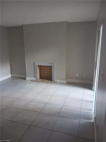 Unfurnished living room featuring light tile patterned flooring and a textured ceiling