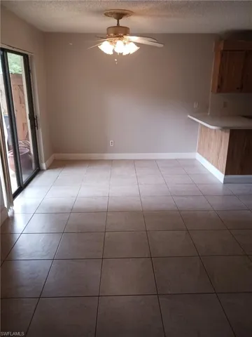Unfurnished dining area with a ceiling fan, a textured ceiling, and light tile patterned floors