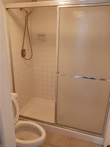Bathroom featuring a shower stall and light tile patterned flooring