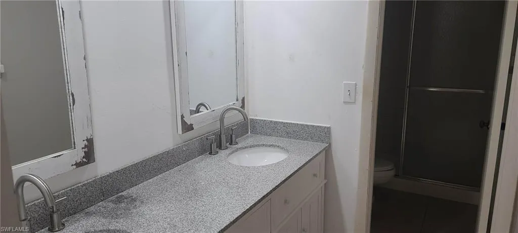 Full bath with double vanity, a shower stall, and tile patterned floors