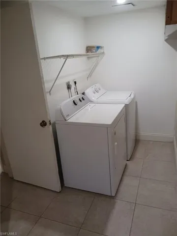 Washroom with light tile patterned floors and separate washer and dryer