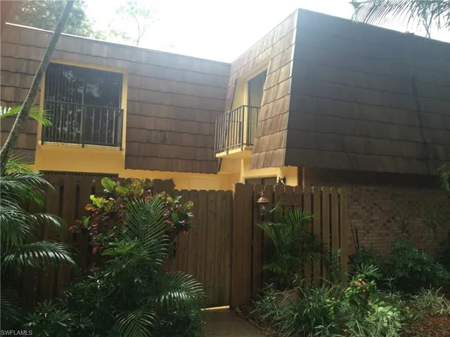View of home's exterior with mansard roof, brick siding, and a balcony