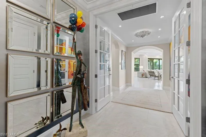 Hall with french doors, arched walkways, crown molding, and recessed lighting