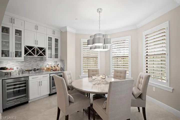 Dining room with beverage cooler, crown molding, a bar, and light tile patterned floors