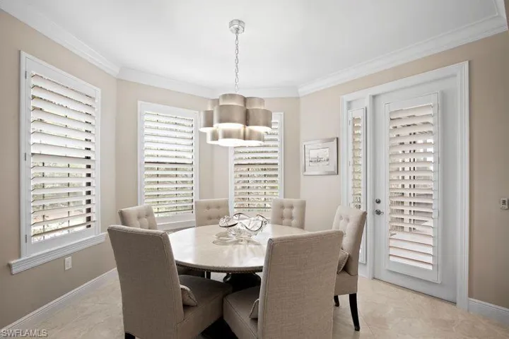 Dining space with a chandelier, ornamental molding, and light tile patterned flooring