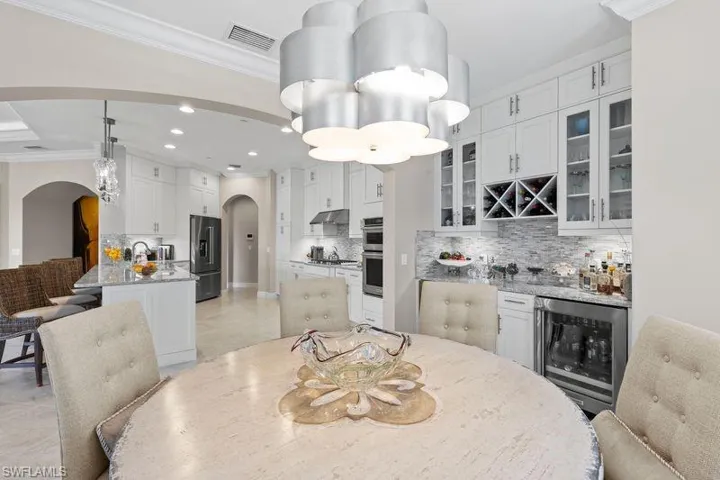 Dining room with ornamental molding, recessed lighting, beverage cooler, arched walkways, and a dry bar
