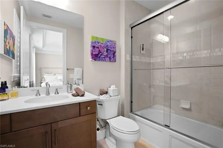 Bathroom with vanity, bath / shower combo with glass door, and connected bathroom