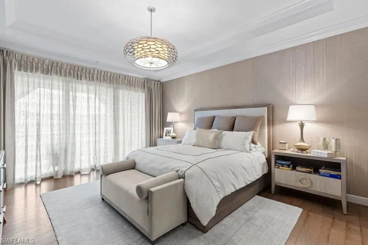 Bedroom featuring hardwood / wood-style floors, a tray ceiling, and ornamental molding