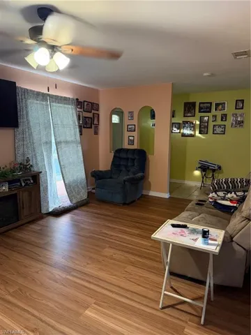Living room with a ceiling fan, arched walkways, and light wood finished floors
