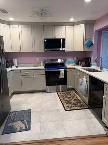 Kitchen with gray cabinetry, stainless steel electric range oven, a ceiling fan, dishwashing machine, and fridge