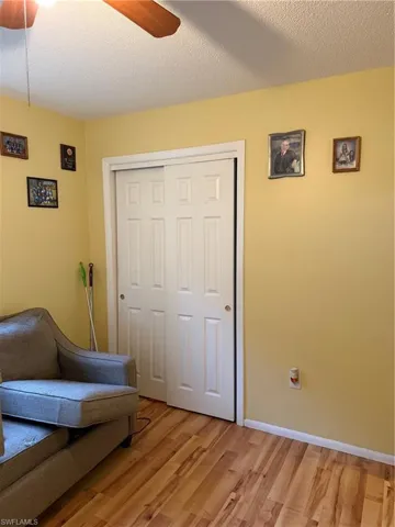 Sitting room with ceiling fan, a textured ceiling, and light wood-style floors