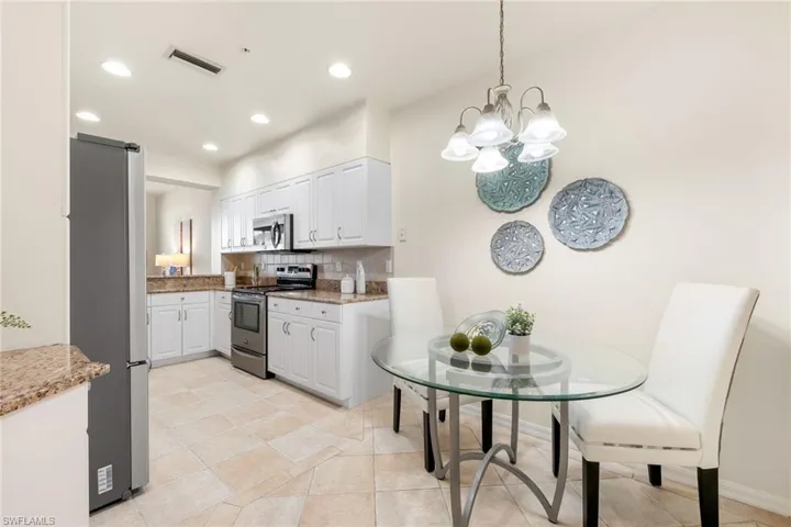 Kitchen with eat-in area and featuring stainless steel appliances, modern white cabinetry, stylish backsplash, light stone granite countertops, and tile floors