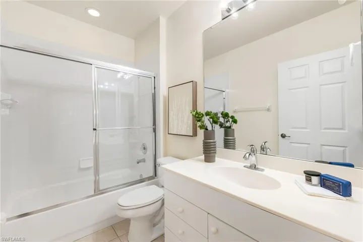 Guest Full bathroom with vanity, bath / shower combo with glass door, tile patterned floors, and toilet