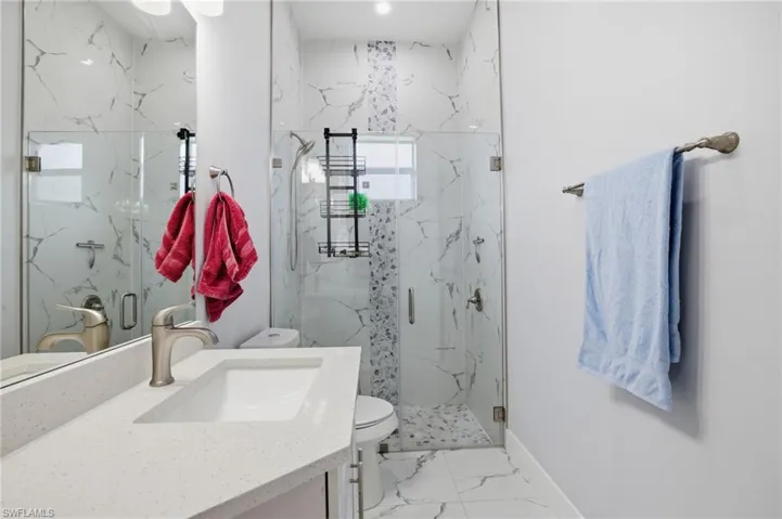 Bathroom with vanity, light marble finish floors, and a marble finish shower