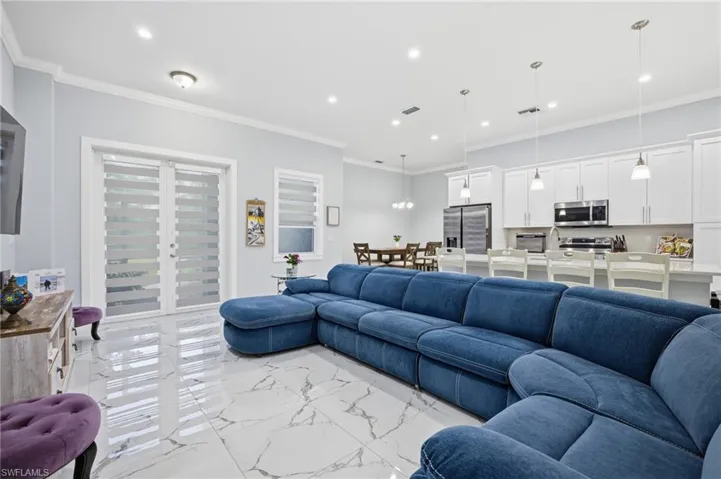 Living room with recessed lighting, crown molding, light marble finish flooring, and french doors