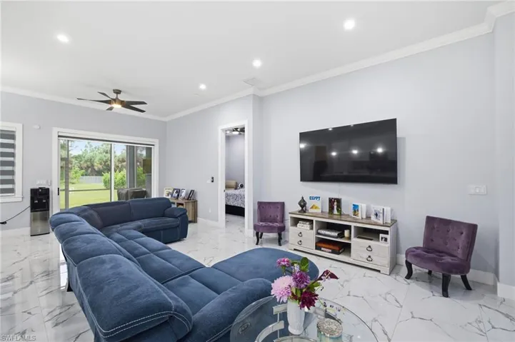 Living room featuring recessed lighting, crown molding, light marble finish floors, and ceiling fan