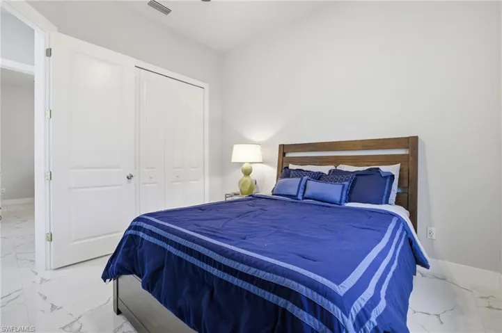 Bedroom with marble look tiles and a closet