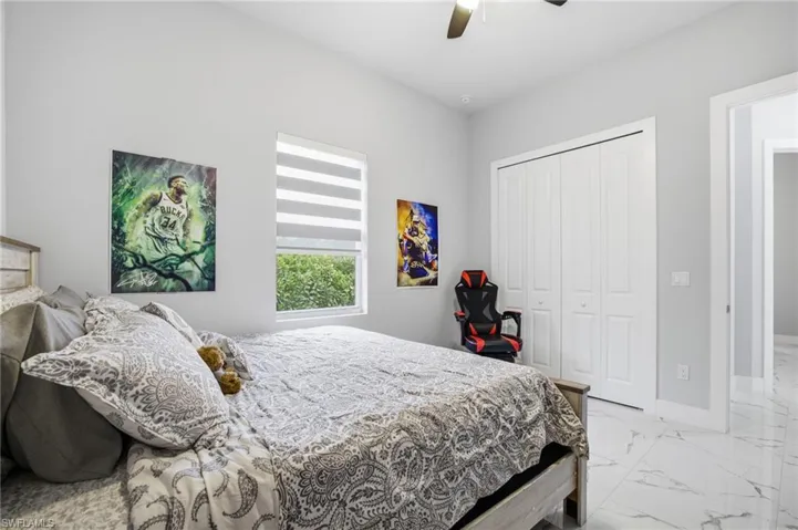 Bedroom featuring light marble finish floors, a closet, and ceiling fan
