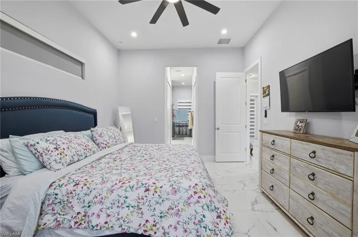 Bedroom with light marble finish flooring, a ceiling fan, recessed lighting, and ensuite bath