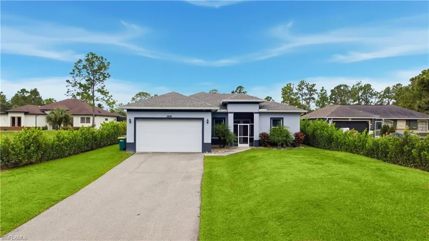 View of front of house with driveway, stucco siding, a front lawn, and an attached garage