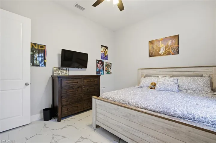 Bedroom with light marble finish floors and ceiling fan