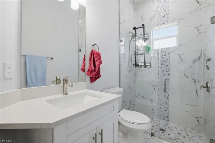 Bathroom featuring vanity and a marble finish shower