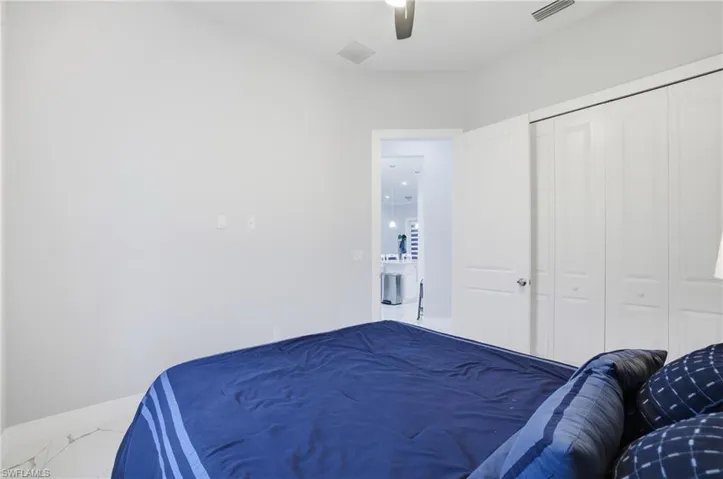 Bedroom with marble finish floors, a ceiling fan, and a closet