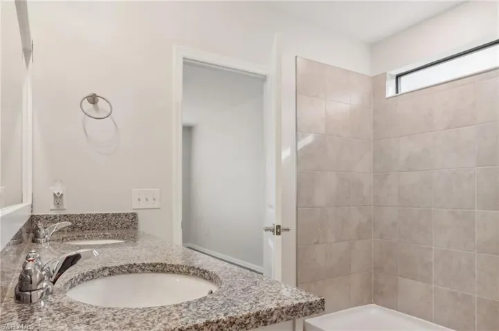 Full bath featuring double vanity, a sink, and tiled shower