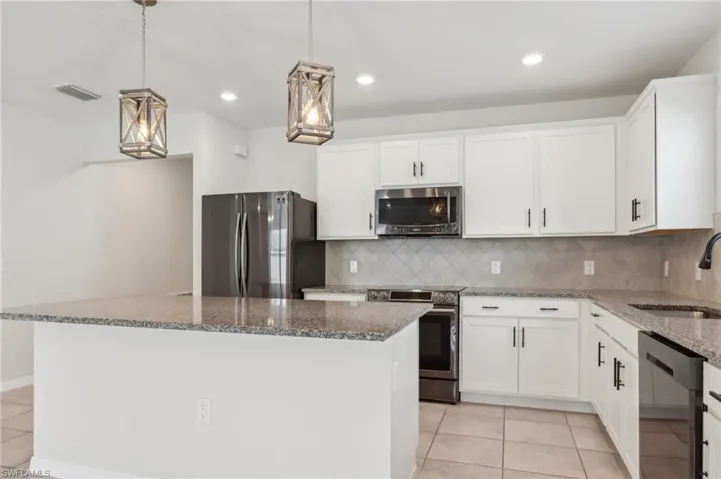 Kitchen with light tile patterned flooring, a sink, stainless steel appliances, and stone countertops