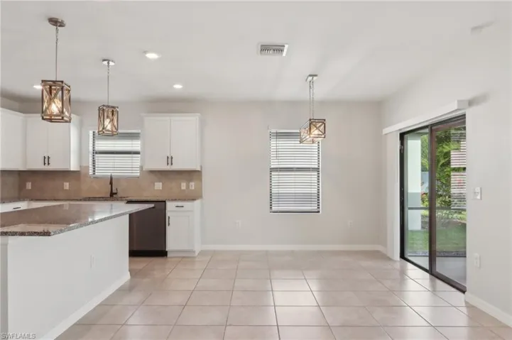 Kitchen with backsplash, white cabinetry, dishwashing machine, visible vents, and dark stone counters