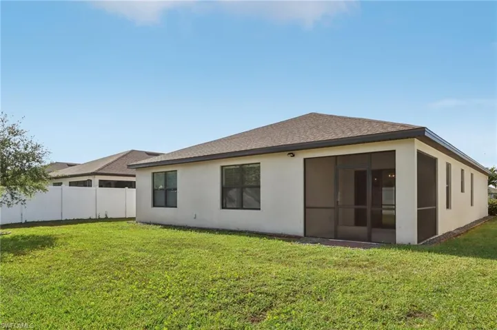 Rear view of house with a sunroom, stucco siding, fence, a shingled roof, and a yard