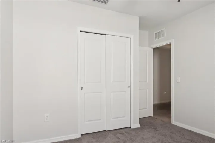 Unfurnished bedroom with baseboards, carpet, a closet, and visible vents