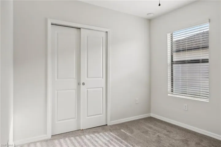Unfurnished bedroom featuring carpet floors, baseboards, and a closet