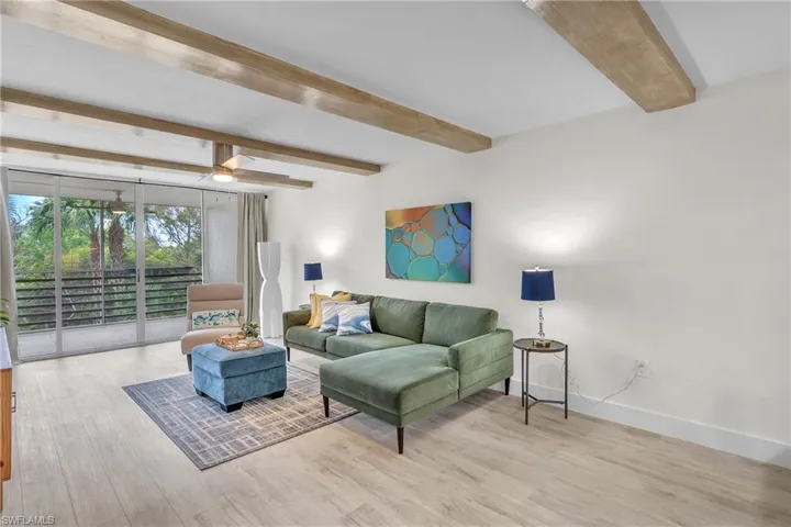 Living room with beam ceiling and light wood-type flooring