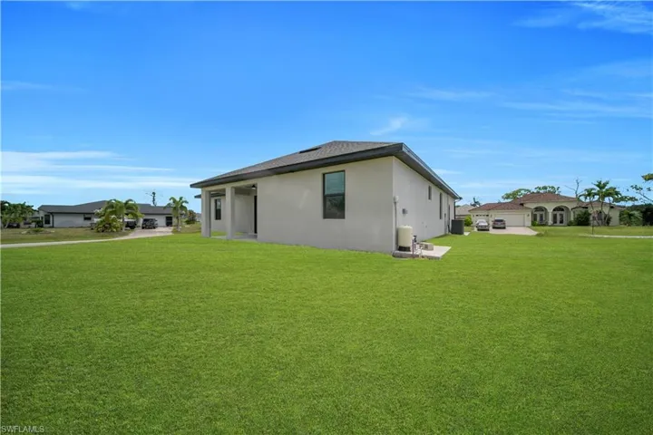 Expansive green lawn surrounds a contemporary stucco exterior with a dark shingle roof and a covered patio area