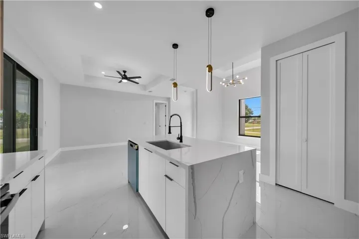 Kitchen island with a waterfall-edge countertop and integrated sink, featuring contemporary pendant lighting