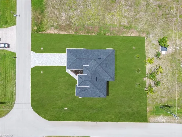Newly constructed property featuring a dark shingle roof and a light-toned paver driveway