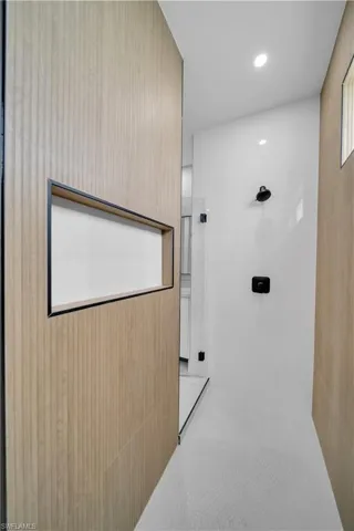 Modern shower enclosure featuring a wood-finish wall with an integrated niche